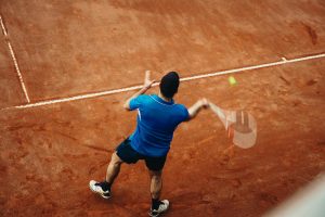 Tay vợt trượt người đánh forehand trên sân đất nện